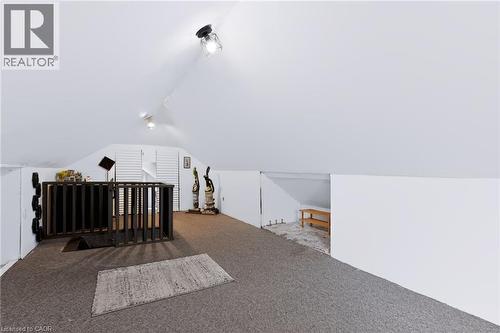 Sloped ceiling attic space featuring track lighting, built-in louvered doors, and a partial wall separation - 703 Brighton Avenue, Hamilton, ON -  Photo Showing Other Room