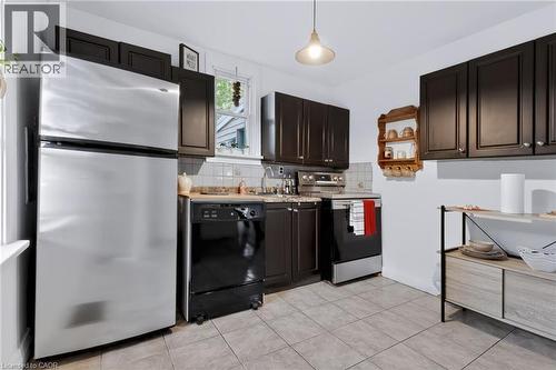 Kitchen featuring dark wood-finish cabinetry, stainless steel refrigerator, black dishwasher, and a stainless steel range - 703 Brighton Avenue, Hamilton, ON - Indoor Photo Showing Kitchen