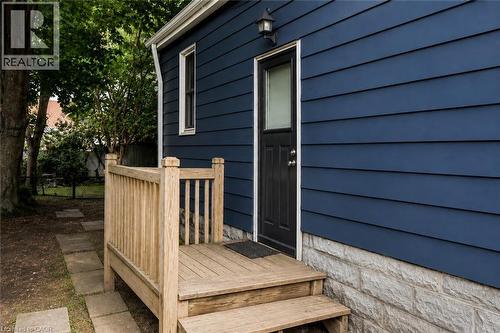 Entry with wood deck and steps, dark blue horizontal siding, and a stone foundation - 703 Brighton Avenue, Hamilton, ON - Outdoor With Exterior