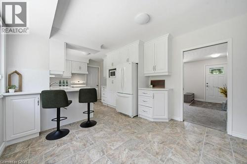White cabinetry with silver hardware, white countertop, tile flooring, and white appliances - 64 Warren Road, Kitchener, ON - Indoor Photo Showing Kitchen