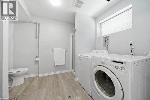 Full bathroom featuring a walk-in shower with a glass enclosure, wood-finish flooring, and a white toilet, within utility room - 64 Warren Road, Kitchener, ON - Indoor Photo Showing Laundry Room