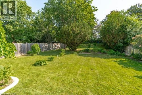 Expansive backyard featuring a manicured lawn, mature trees, established garden beds, and a wood privacy fence - 64 Warren Road, Kitchener, ON - Outdoor