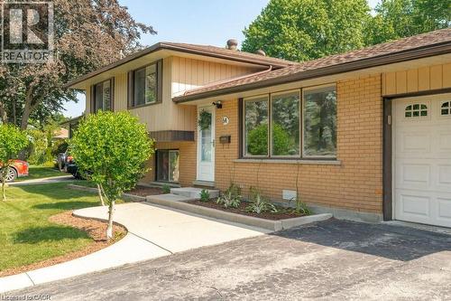 Brick facade with siding, asphalt shingle roof, attached garage with panel door, concrete walkway, and manicured landscaping - 64 Warren Road, Kitchener, ON - Outdoor