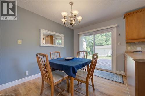 Wood-finish flooring, sliding glass door, overhead chandelier, light wood cabinetry, and a tile backsplash - 251 Union Street E, Waterloo, ON - Indoor Photo Showing Dining Room