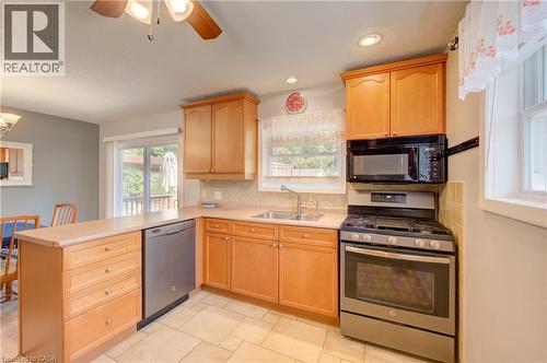 Kitchen featuring wood cabinetry, stainless steel appliances, tile flooring, and a sliding glass door - 251 Union Street E, Waterloo, ON - Indoor Photo Showing Kitchen With Double Sink