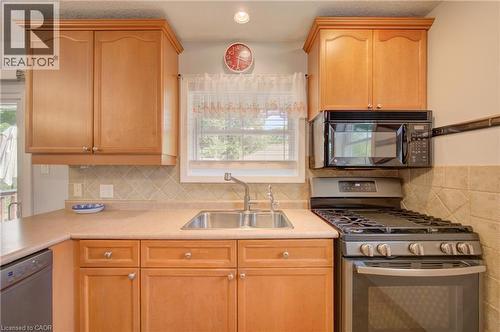 Light wood-finish cabinetry, stainless steel double basin sink, tile backsplash, stainless steel gas range, and a built-in microwave - 251 Union Street E, Waterloo, ON - Indoor Photo Showing Kitchen With Double Sink