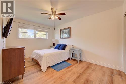 Wood-finish flooring with white baseboards, a ceiling fan with light fixture, and double windows with roller shades - 251 Union Street E, Waterloo, ON - Indoor Photo Showing Bedroom