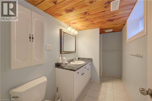Wood-finish ceiling panels, white vanity with integrated sink, dark countertop, framed mirror, and tiled flooring - 251 Union Street E, Waterloo, ON - Indoor Photo Showing Bathroom