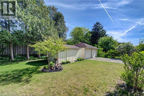 Detached two-car garage with overhead doors, expansive green lawn, mature trees, and privacy fencing - 251 Union Street E, Waterloo, ON - Outdoor