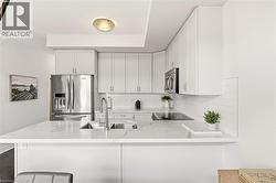 Kitchen featuring white shaker cabinetry, stainless steel appliances, white subway tile backsplash, and light-toned countertops - 