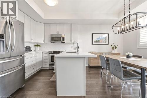 Modern kitchen and dining area featuring white shaker cabinetry, stainless steel appliances including French-door refrigerator and gas range, white quartz waterfall island with undermount sink and goo - 4171 Palermo Common, Burlington, ON - Indoor Photo Showing Kitchen With Upgraded Kitchen