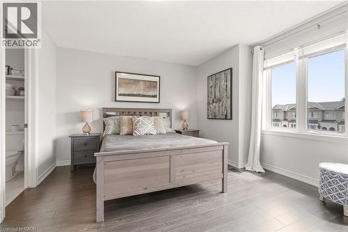 Wood-finish flooring, light grey wall paint, and a large window with white trim - 4171 Palermo Common, Burlington, ON - Indoor Photo Showing Bedroom