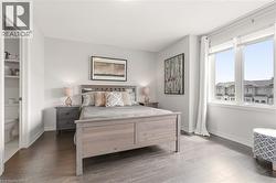 Wood-finish flooring, light grey wall paint, and a large window with white trim - 