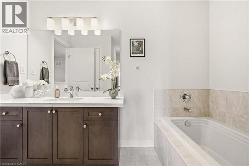 Spa-inspired primary bathroom featuring a dark wood vanity with dual sinks, marble-topped countertop, and large framed mirror with integrated lighting - 4171 Palermo Common, Burlington, ON - Indoor Photo Showing Bathroom