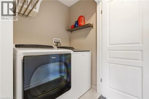 Dedicated laundry room featuring a front-load Whirlpool dryer with a white finish, matching countertop workspace, floating shelving, recessed ceiling lighting, and neutral wall finishes - 4171 Palermo Common, Burlington, ON - Indoor Photo Showing Laundry Room
