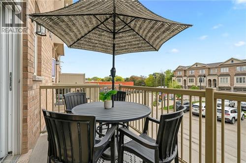 Balcony with a brick exterior, metal railing, and an exterior light fixture - 4171 Palermo Common, Burlington, ON - Outdoor With Exterior