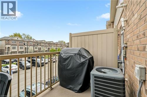 Private balcony featuring a metal railing with views of the surrounding residential community, equipped with HVAC units and a protective cover for seasonal storage - 4171 Palermo Common, Burlington, ON - Outdoor With Exterior