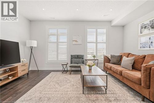 Bright, open living room showcasing dark wood-finish flooring, recessed ceiling lighting, and plantation shutter doors - 4171 Palermo Common, Burlington, ON - Indoor Photo Showing Living Room