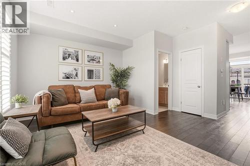 Recessed lighting, wood-finish flooring, white plantation shutters, three-panel interior door, and a built-in vanity with a vessel sink - 4171 Palermo Common, Burlington, ON - Indoor Photo Showing Living Room