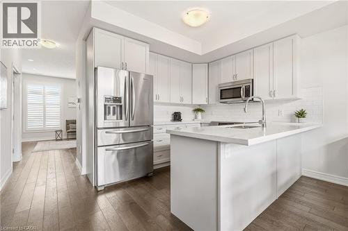 White shaker cabinetry, stainless steel appliances, white subway tile backsplash, white countertop, and wood-finish flooring - 4171 Palermo Common, Burlington, ON - Indoor Photo Showing Kitchen With Stainless Steel Kitchen With Upgraded Kitchen