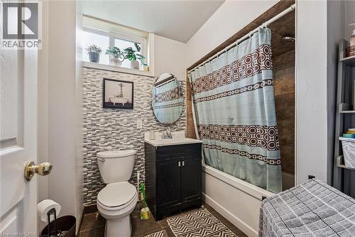 Bathroom featuring a tub/shower combination with tile surround, a single vanity with a round mirror, and a window for natural light - 27 Roseview Avenue, Cambridge, ON - Indoor Photo Showing Bathroom