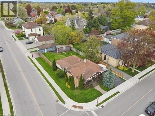 Aerial view showcasing a substantial corner-lot property with a brick exterior, mature landscaping including evergreen specimens, a covered patio structure, and manicured lawn - 27 Roseview Avenue, Cambridge, ON - Outdoor With View