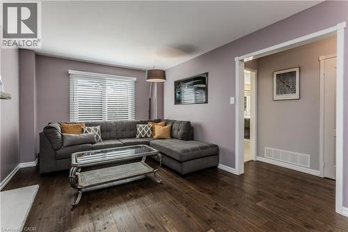 Wood-finish flooring throughout, featuring a window with horizontal blinds and a doorway with white trim - 1238 Sable Drive, Burlington, ON - Indoor Photo Showing Living Room
