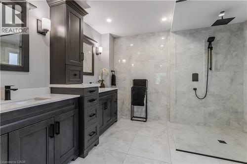 Dual vanity with integrated sinks, dark wood-finish cabinetry, white countertops, matte black fixtures, and a glass-enclosed shower with a rainfall showerhead - 1238 Sable Drive, Burlington, ON - Indoor Photo Showing Bathroom