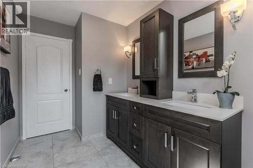 Double vanity with integrated sinks, light-toned countertops, dark wood-finish cabinetry, and framed mirrors - 1238 Sable Drive, Burlington, ON - Indoor Photo Showing Bathroom