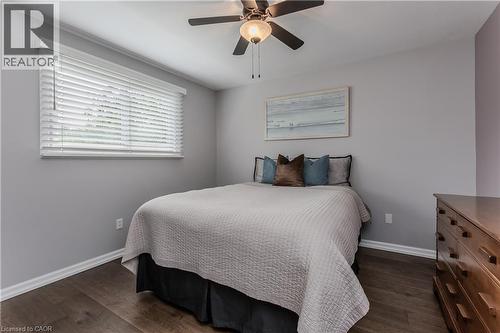 Wood-finish flooring, ceiling fan with light fixture, window with blinds, and neutral wall tones - 1238 Sable Drive, Burlington, ON - Indoor Photo Showing Bedroom