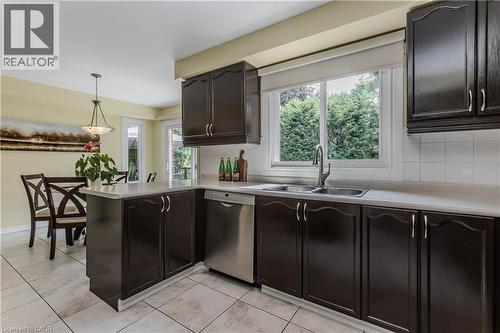 Kitchen featuring dark wood-finish cabinetry, light countertops, and a double basin sink - 1238 Sable Drive, Burlington, ON - Indoor Photo Showing Kitchen With Double Sink