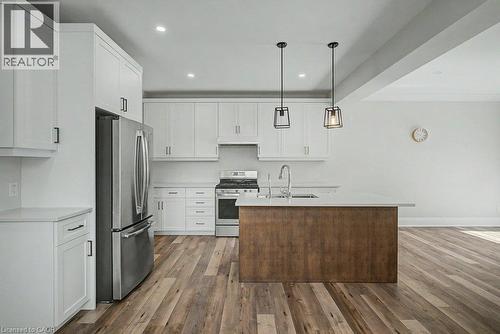 Modern kitchen featuring white cabinetry, stainless steel appliances, a wood-finish island with a countertop, and recessed lighting - 31 Fourth Avenue, Kitchener, ON - Indoor Photo Showing Kitchen