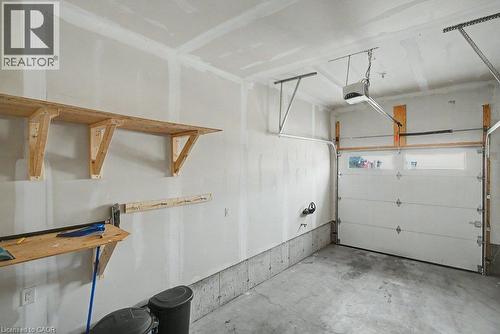 Attached garage featuring a concrete floor, built-in wooden shelving, and an automatic garage door opener - 31 Fourth Avenue, Kitchener, ON - Indoor Photo Showing Garage