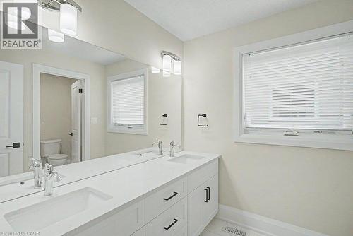 Dual vanity with under-mount sinks, sleek chrome faucets, white cabinetry, and a large wall-mounted mirror - 31 Fourth Avenue, Kitchener, ON - Indoor Photo Showing Bathroom