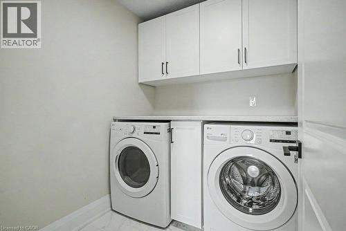 White shaker-style cabinetry with dark hardware, solid surface countertop, and white tile flooring - 31 Fourth Avenue, Kitchener, ON - Indoor Photo Showing Laundry Room