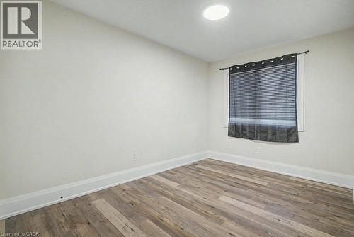 Wood-finish flooring with white baseboards, recessed ceiling lighting, and a window with blinds - 31 Fourth Avenue, Kitchener, ON - Indoor Photo Showing Other Room