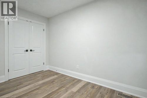 White double doors with matte black hardware, wood-finish flooring, and white trim - 31 Fourth Avenue, Kitchener, ON - Indoor Photo Showing Other Room