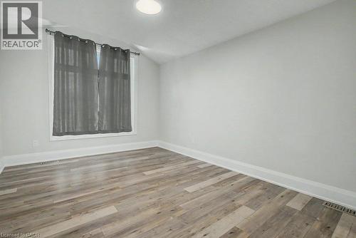 Recessed ceiling lighting illuminates the room, featuring wood-finish flooring and a single window with white trim - 31 Fourth Avenue, Kitchener, ON - Indoor Photo Showing Other Room