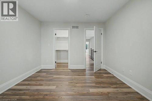 Wood-finish flooring, white walls, white trim, recessed lighting, and a closet with built-in shelving - 31 Fourth Avenue, Kitchener, ON - Indoor Photo Showing Other Room