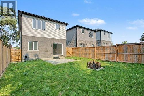 Fenced backyard with a concrete patio, sliding glass door access, and a fire pit - 31 Fourth Avenue, Kitchener, ON - Outdoor