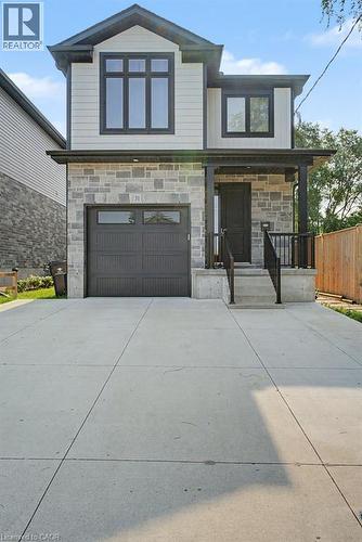 Contemporary exterior featuring stone and siding, an attached garage, a covered front entry, and a paved driveway - 31 Fourth Avenue, Kitchener, ON - Outdoor