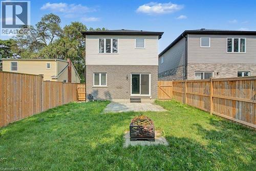 Rear exterior with a stone and siding facade, featuring multiple windows and a sliding glass door - 31 Fourth Avenue, Kitchener, ON - Outdoor With Exterior