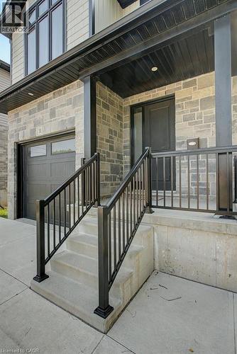 Stone veneer exterior with light-toned siding, black garage door, covered entry, and black metal railings - 31 Fourth Avenue, Kitchener, ON - Outdoor With Exterior