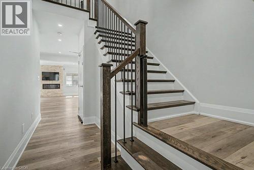 Hardwood flooring throughout, modern staircase with wrought iron balusters, recessed lighting, and a stone-clad fireplace feature wall - 31 Fourth Avenue, Kitchener, ON - Indoor Photo Showing Other Room