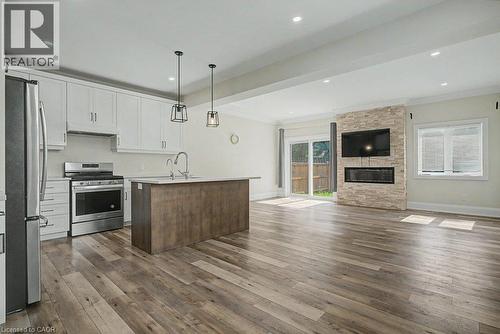 White shaker-style cabinetry, stainless steel appliances, wood-finish flooring, stone-clad fireplace, and recessed lighting - 31 Fourth Avenue, Kitchener, ON - Indoor