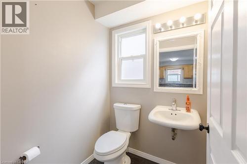 White pedestal sink with chrome faucet, framed mirror, and a four-bulb vanity light fixture - 248 Bridlewreath Street, Kitchener, ON - Indoor Photo Showing Bathroom