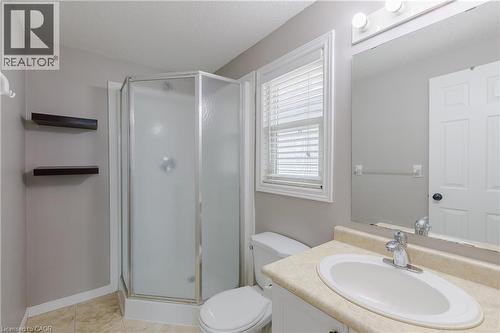 Corner shower enclosure, single vanity with integrated sink, wall-mounted mirror, and tile flooring - 248 Bridlewreath Street, Kitchener, ON - Indoor Photo Showing Bathroom