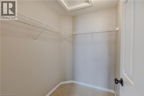 Walk-in closet with wire shelving, integrated hanging rods, panel door, and neutral wall paint - 248 Bridlewreath Street, Kitchener, ON - Indoor With Storage