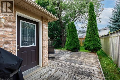 Wood deck with a brick exterior, featuring a door with decorative glass, and established evergreen trees - 248 Bridlewreath Street, Kitchener, ON - Outdoor With Deck Patio Veranda