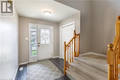 Entryway featuring wood-finish flooring, a white door with decorative glass, and a carpeted staircase with a wood railing - 248 Bridlewreath Street, Kitchener, ON - Indoor Photo Showing Other Room